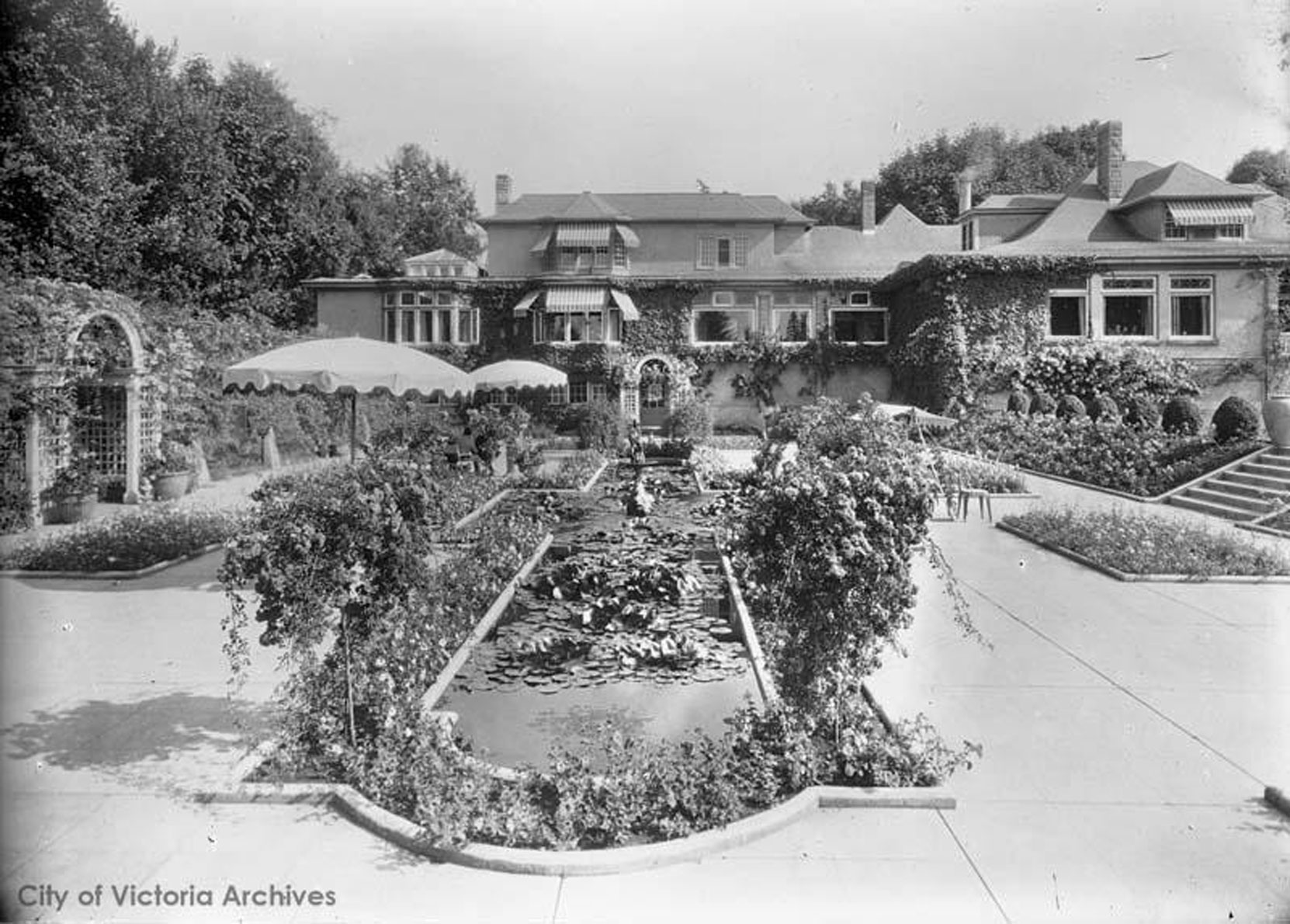 Benvenuto and the Italian Garden circa 1926-1927, prior to the addition designed by architect Samuel Maclure for the east side of Benvenuto. The Roas Arbors designed by Samuel Maclure are also visible in this photograph. (City of Victoria Archives photo M07113)