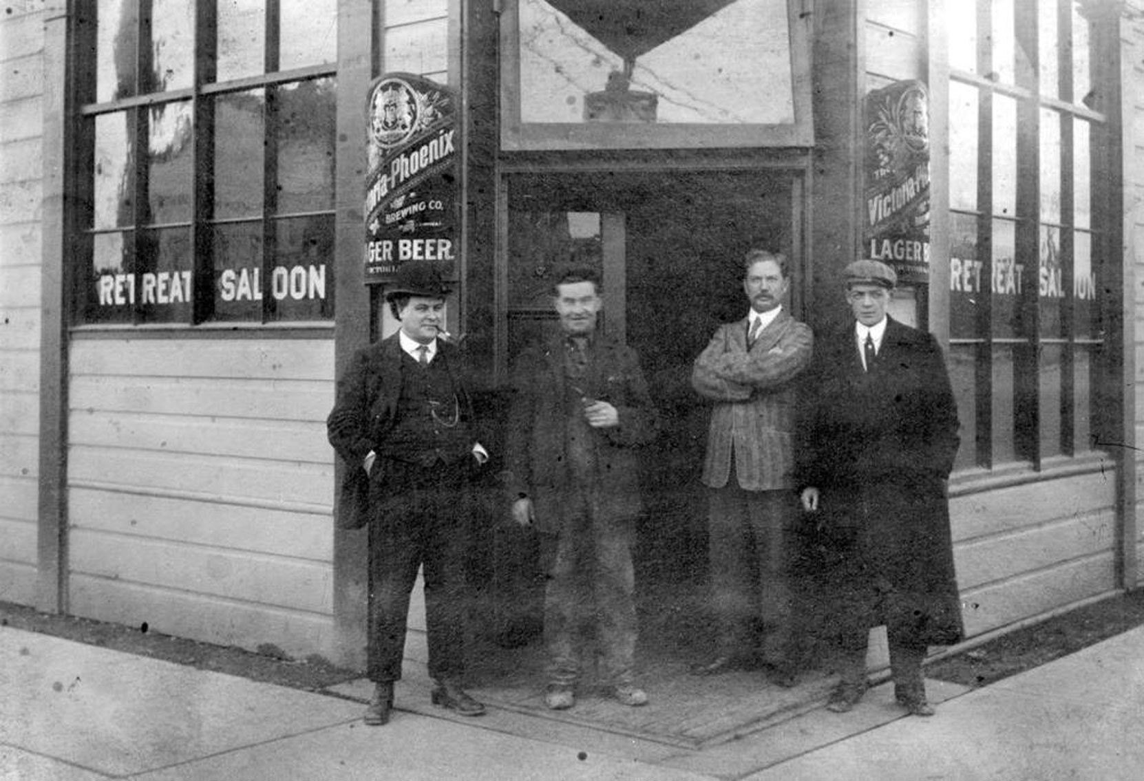 Four unidentified men outside Joseph Wrigglesworth's Retreat Saloon, on the southeast corner of Yates Street and Blanshard Street in downtown Victoria, circa 1900. Note the sign for Victoria-Phoenix Lager Beer, brewed by a Victoria based brewery. (BC Archives photo C-08971)